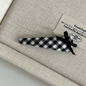 Detailed close-up of a black and white gingham BB hair clip with a ribbon bow