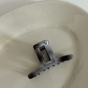 Close-up of square acetate hair claw clip with grey marble ink pattern and metal spring