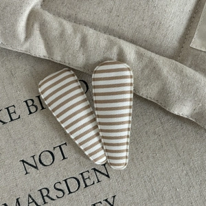 Close-up of brown and beige striped fabric hair clips on a natural canvas background
