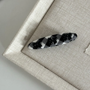 Detail of plaid barrette with three black bows on textured fabric background