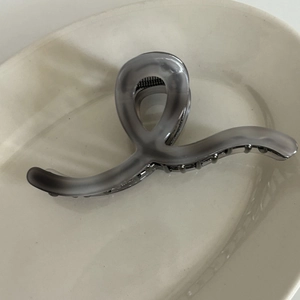 Macro shot of grey ink-wash acetate hair claw clip showing smooth texture and metal spring