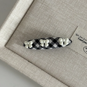 Detail view of British style gingham hair clip with three white bows on fabric base