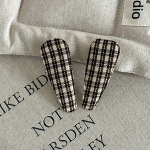 Detail of brown plaid fabric covered BB hair clips on minimalist canvas background