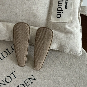 Close-up of brown textured fabric hair clips on linen background in minimalist retro style