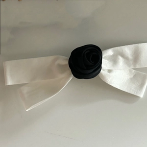 Close-up of white silk ribbon bow with a black fabric rose center for hair styling