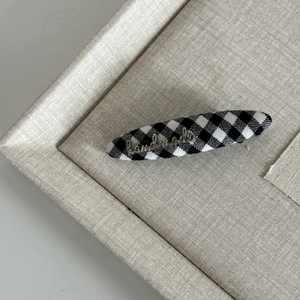 Detail view of British style gingham hair clip with a gold handmade metal logo