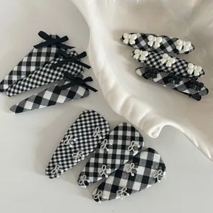Detail of 9-piece black and white gingham hair clips with resin and diamond bows