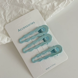 Trois barrettes ondulées bleu clair nacré présentées sur une carte de support