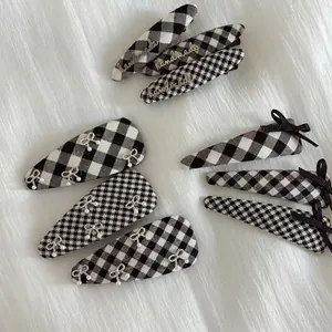 British style black and white plaid bow hair clip set with pearls on white plush background
