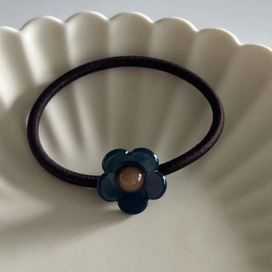 Eleganter Haargummi mit dunkelblauer Harzblume auf weißem Keramikteller für Damen