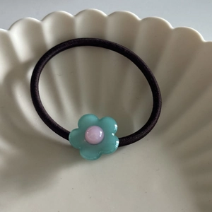 Blassgrünes Acetat-Blumenhaargummi mit rosa Perle auf hochelastischem braunem Band
