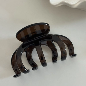 Detail of a large brown translucent octopus hair claw clip on a white ceramic plate