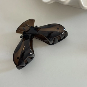 Detail view of two deep brown translucent resin claw clips with amber texture