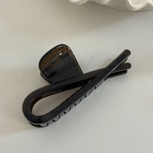 Detail of a large brown translucent resin claw clip with cross-loop design and anti-slip teeth