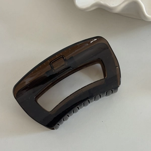 Detail of a large dark brown translucent rectangle hollow hair claw clip with spring
