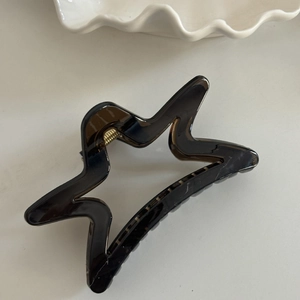 Close-up of tortoise shell star-shaped hair claw clip with golden metal spring