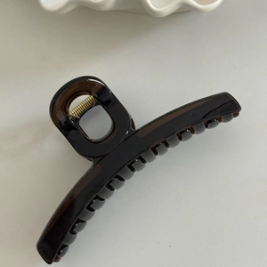 Macro detail of amber brown hair claw clip with golden metal spring for thick hair