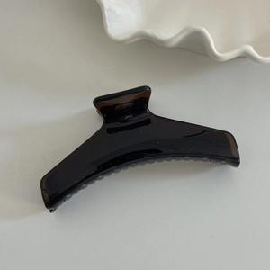 Detailed close-up of large amber resin hair claw clip with glossy finish and strong grip teeth
