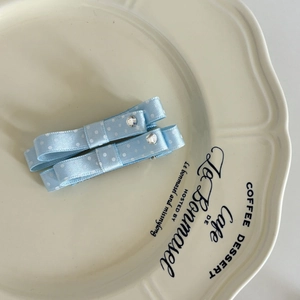 Detailed view of light blue polka dot bow hair clips with rhinestones in a tray