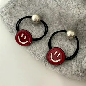 Élastique à cheveux rouge en acétate avec smiley et perles sur tricot gris