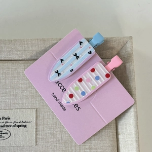 Détail de deux barrettes à cheveux faites main avec motifs de nœuds sur carton