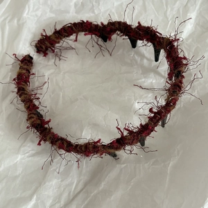 Dettaglio della trama a maglia bordeaux e denti ondulati sulla fascia imbottita