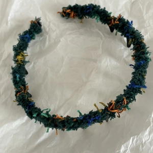 Dettaglio del cerchietto in maglia verde scuro con puntini colorati e denti antiscivolo