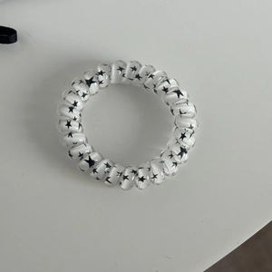 Close-up of transparent spiral hair tie featuring black star patterns and elastic texture