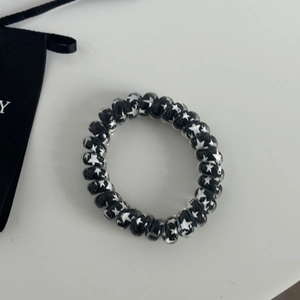 Close-up of black spiral telephone wire hair tie with white star patterns on white desk