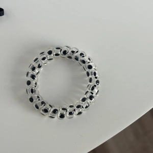 Close-up of spiral hair tie with black polka dot patterns in clear plastic material