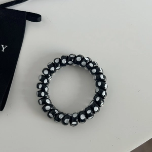 Close-up of black spiral hair tie with white polka dots on a clean white background