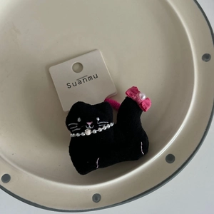 Cute black plush cat hair clip with pearl necklace and lace bow on a ceramic tray
