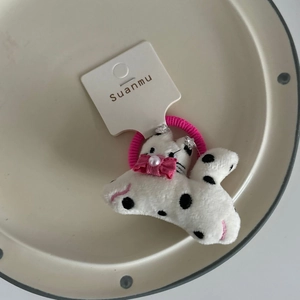 Detail of plush dalmatian hair tie with pink bow and pearl on ceramic plate