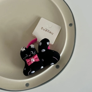 Detail of black plush cat hair tie with pink bow, pearl accent and silver star decoration