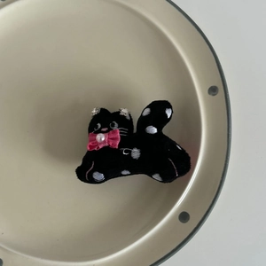 Detail of cute black velvet cat hair clip with pink bow, pearl and polka dots