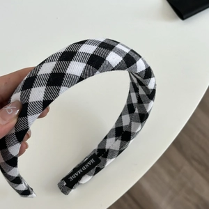 Detail of handmade gingham headband with black and white checkered pattern and woven tag