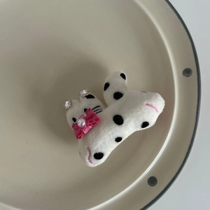 Close-up of plush cat ear hair clip with polka dots, pink bow, and pearl details