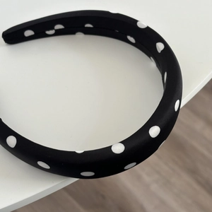 Detailed macro view of the padded black satin headband with large white polka dots texture