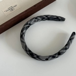Detail of checkered headband with polka dots and handmade fabric label on white surface