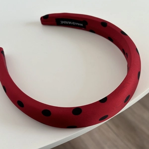 Detail of red satin polka dot headband with handmade label and soft sponge filling