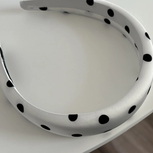Detail of white satin headband with black polka dots featuring a retro padded 3D design