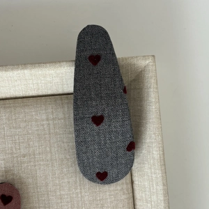 Close-up of grey cotton BB hair clip featuring red flocked hearts in a display box