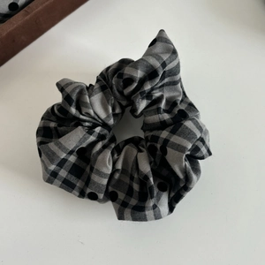Detail of grey plaid scrunchie with black polka dots and soft fabric texture
