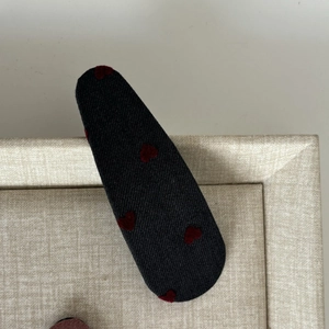 Close-up of heart-patterned denim hair clip with red flocked hearts on blue fabric