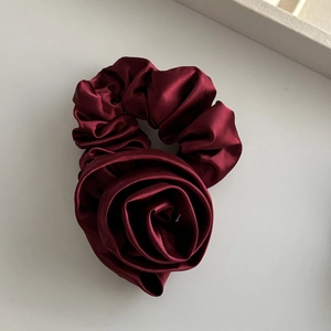 Macro view of burgundy satin rose scrunchie with French style elegant glossy texture