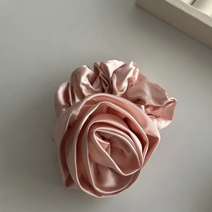Close-up of elegant champagne pink satin rose hair tie with refined silk texture and layers