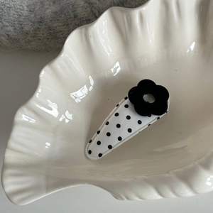 White fabric hair clip with black polka dots and a flocked flower on a shell plate