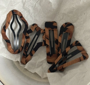 Detail view of 5-piece leopard print hair clips with fabric covering on black metal base