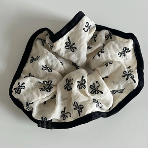 Close-up of lace polka dot scrunchie featuring black bow prints and satin piping