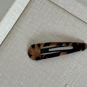 Detailed view of leopard print fabric texture on a square black snap hair clip